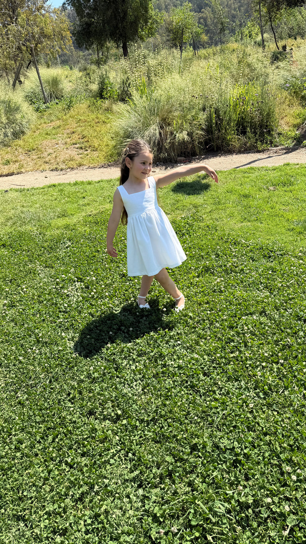 Vestido infantil en lino blanco con aire mediterráneo y espalda con smocking artesanal. Forro en algodón pima hipoalergénico. Diseño de lujo sostenible Riso di Luna.