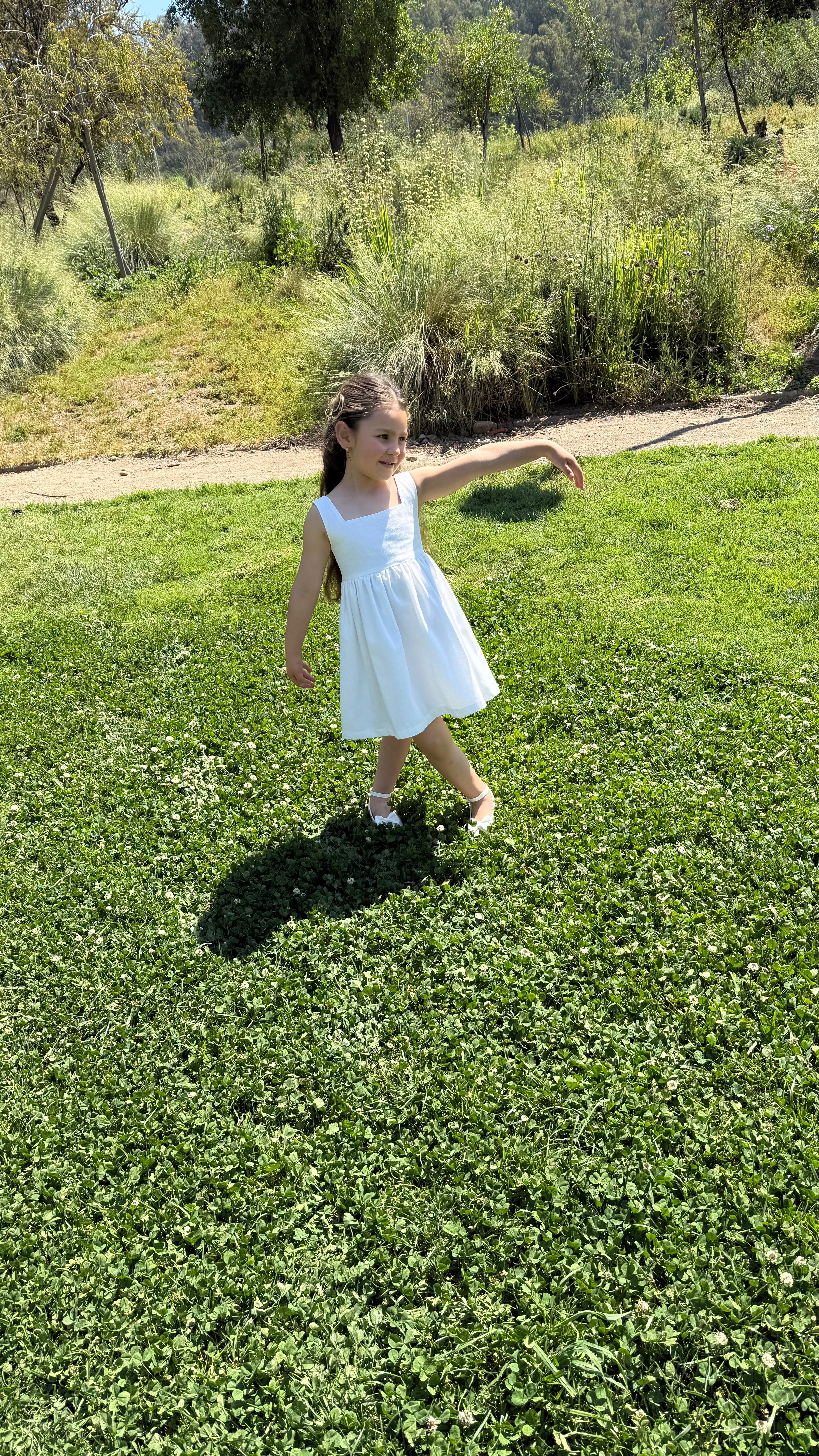 Vestido infantil en lino blanco con aire mediterráneo y espalda con smocking artesanal. Forro en algodón pima hipoalergénico. Diseño de lujo sostenible Riso di Luna.