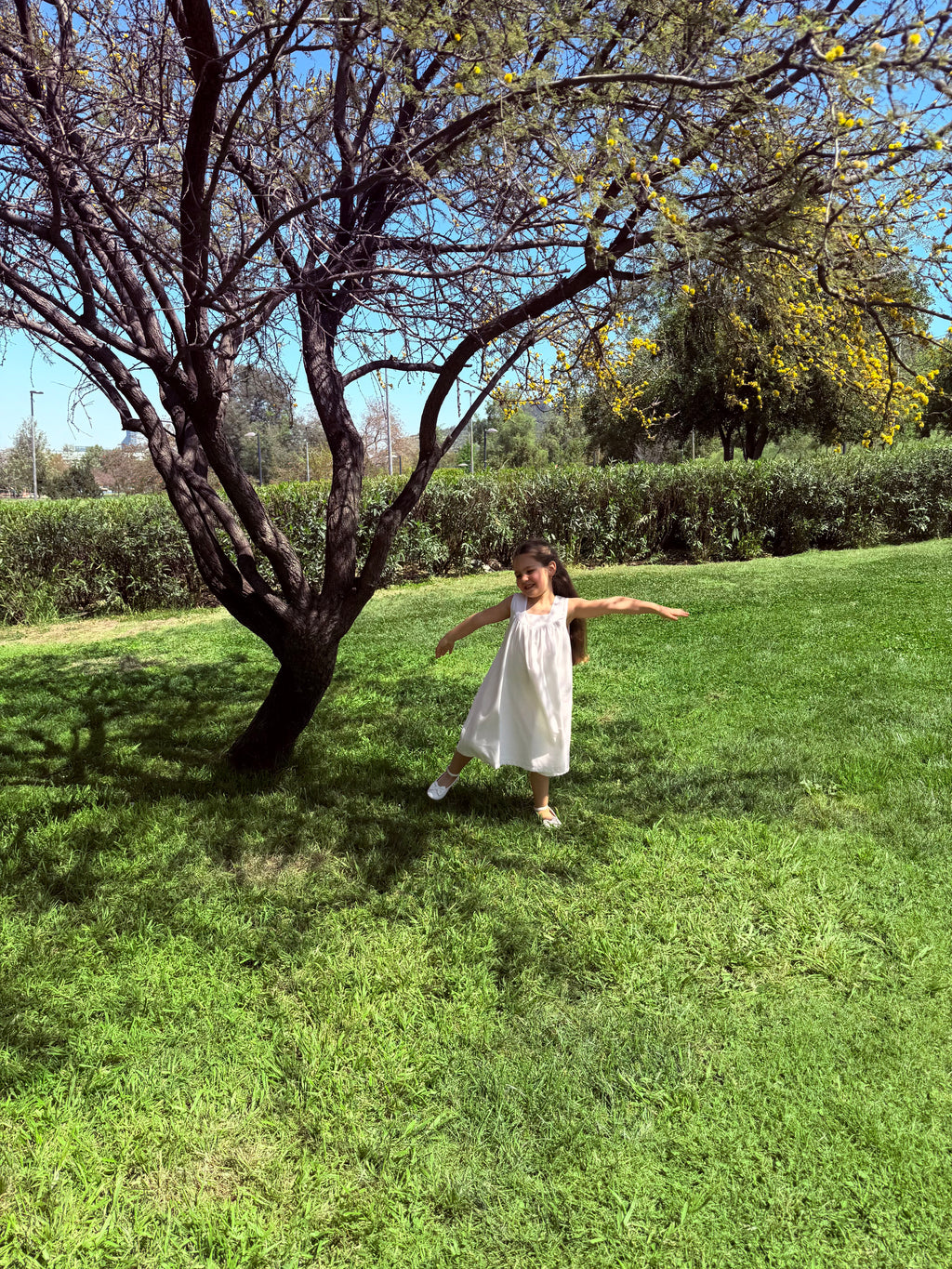 Vestido infantil en lino blanco con aire mediterráneo y smocking artesanal. Forro en algodón pima hipoalergénico. Lavar a mano. Diseño de lujo sostenible Riso di Luna.