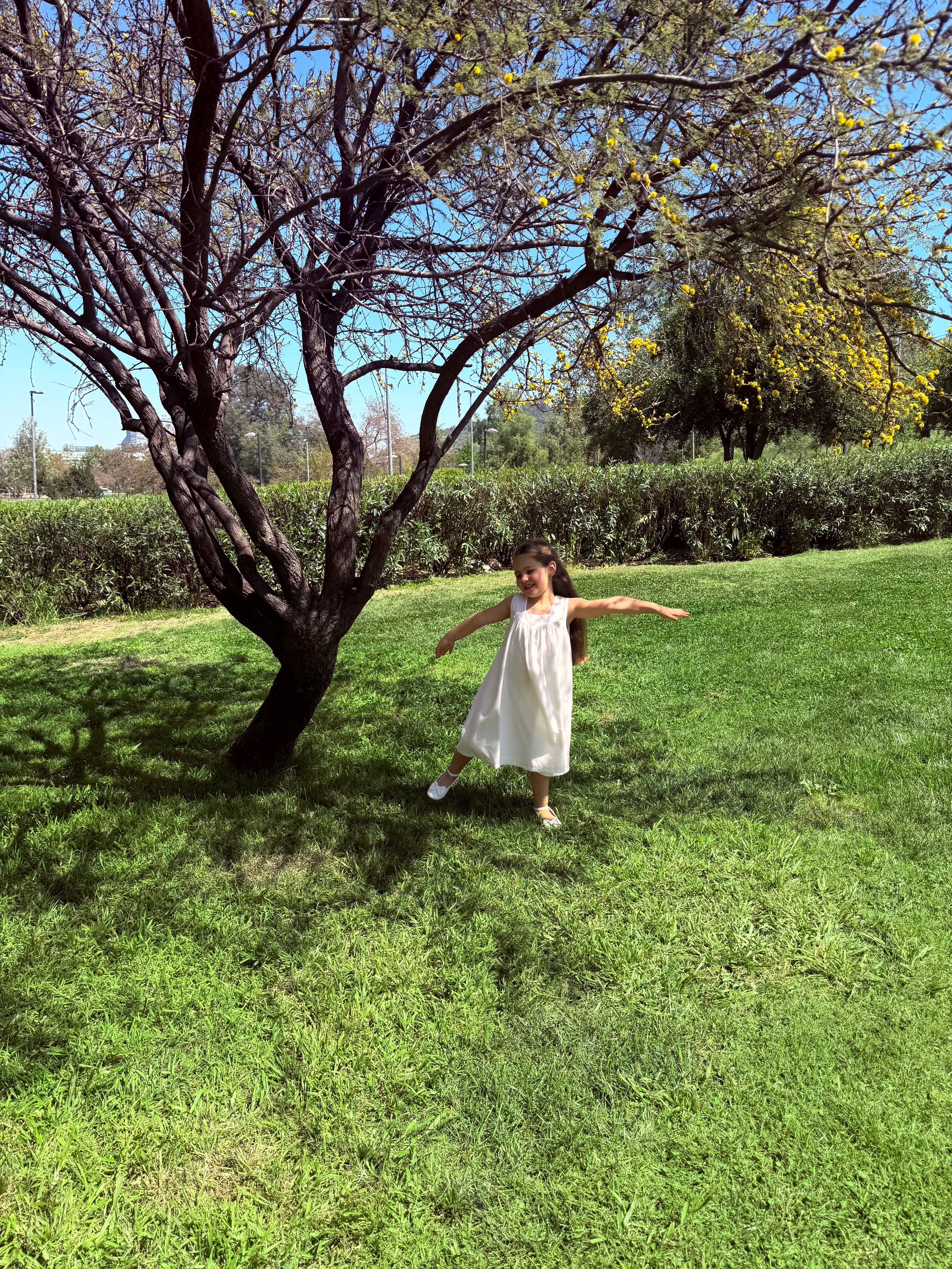 Vestido infantil en lino blanco con aire mediterráneo y smocking artesanal. Forro en algodón pima hipoalergénico. Lavar a mano. Diseño de lujo sostenible Riso di Luna.
