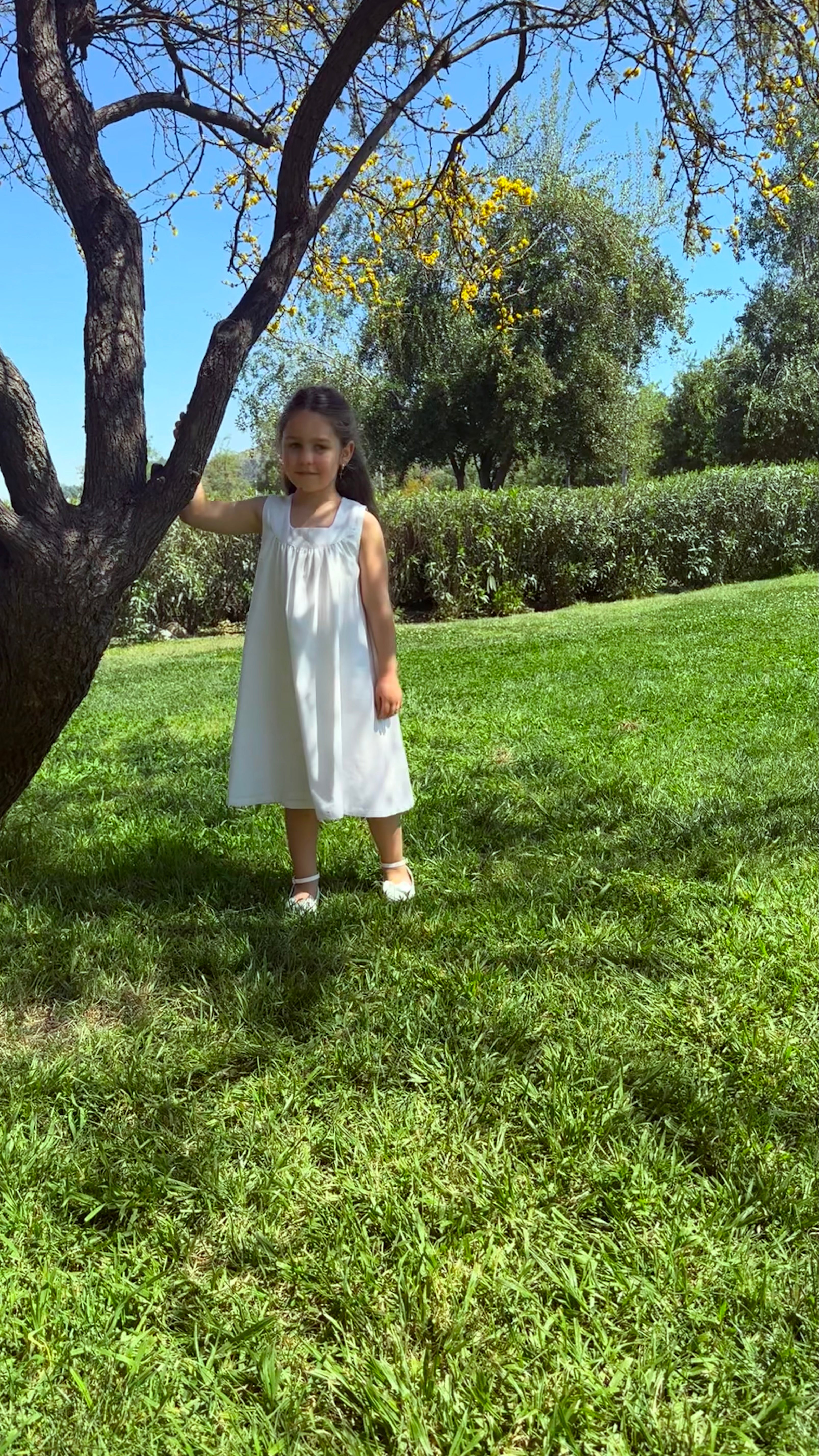 Vestido infantil en lino blanco con aire mediterráneo y smocking artesanal. Forro en algodón pima hipoalergénico. Lavar a mano. Diseño de lujo sostenible Riso di Luna.